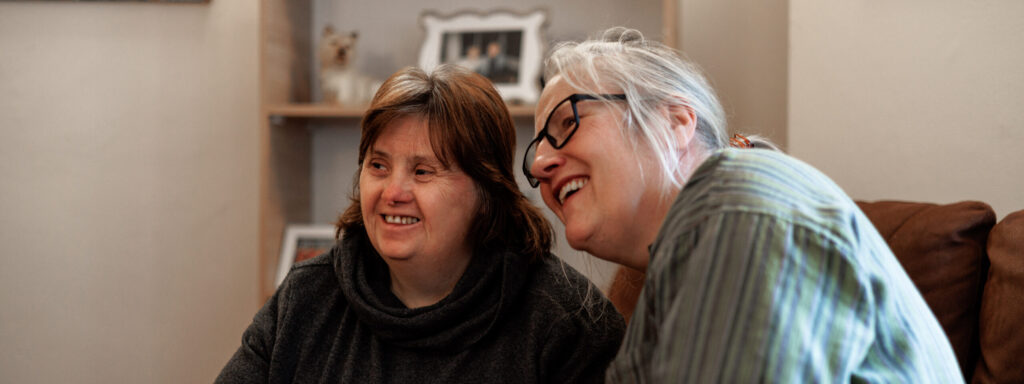 Birmingham Supported Living woman and carer smiling at camera in the corner