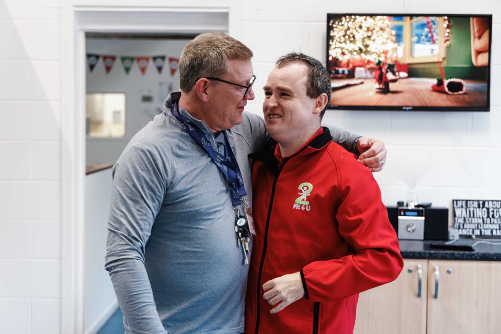 Praxis Care disabled person and support worker hugging